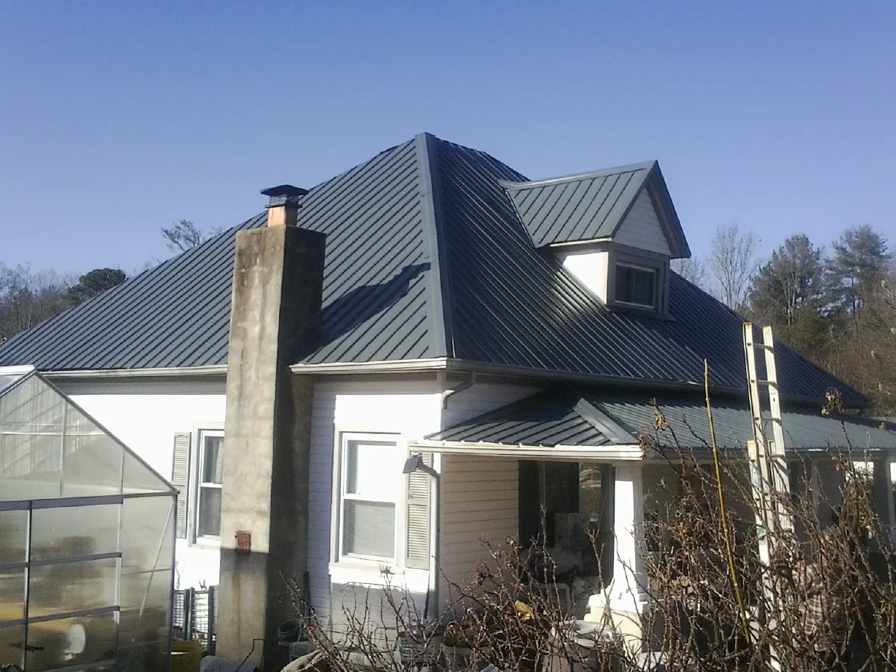 Dark blue standing seam metal roof on a white farmhouse with dormer — Slate & Tile Roof Repair by Roofing Brothers in Sunol