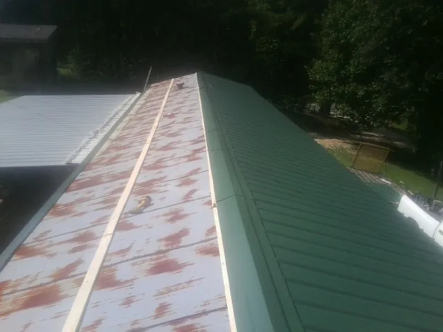 Old rusted panels beside newly installed green metal roofing — Wind Damage Roof Repair by Roofing Brothers in Sunol