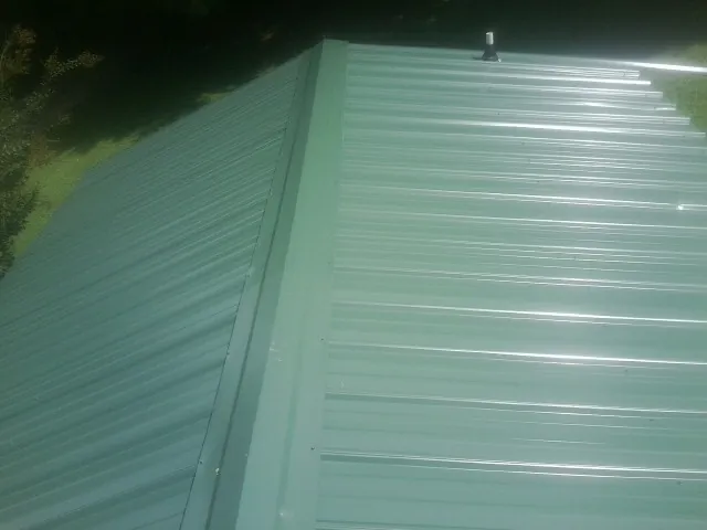 New green metal panels meeting at the ridge of a roof — Flat Roof Repair work by our crew in Sunol
