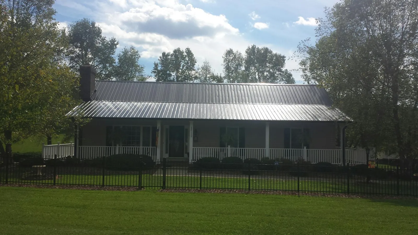 Gray metal roof on a brick ranch with a full width front porch — Gutter Guard Installation work by our crew in Sunol