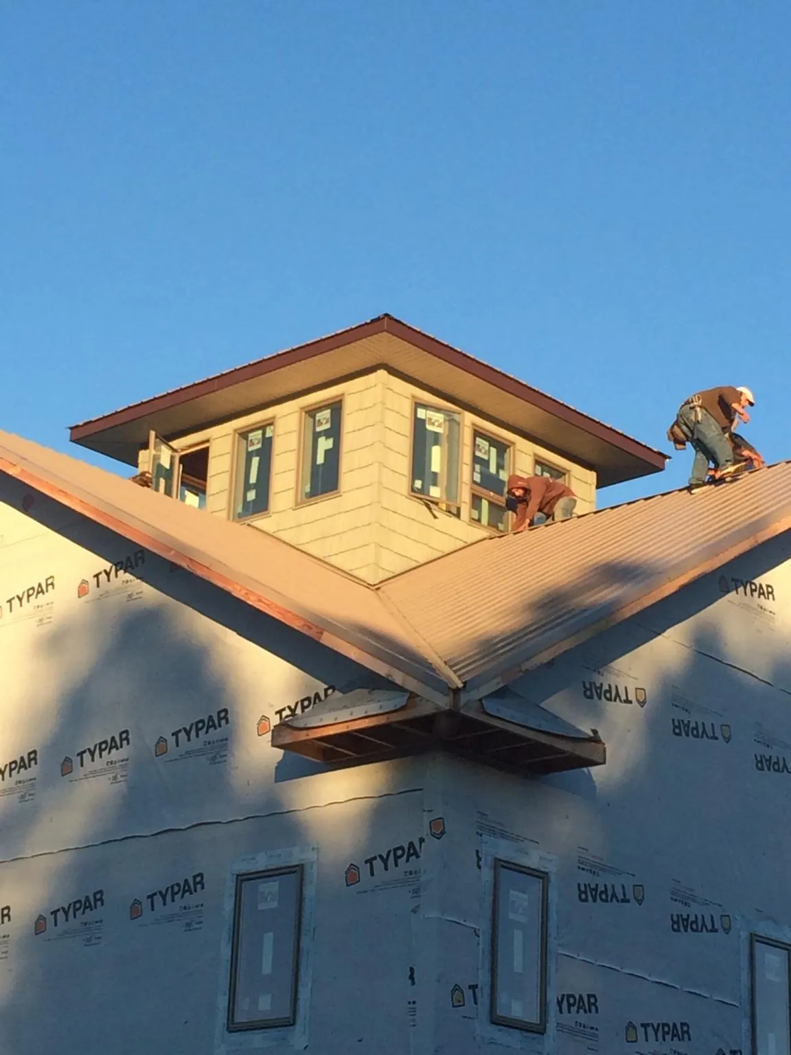 Roofers working around a rooftop cupola on a new metal roof at sunset — Roof Waterproofing in Sunol by Roofing Brothers